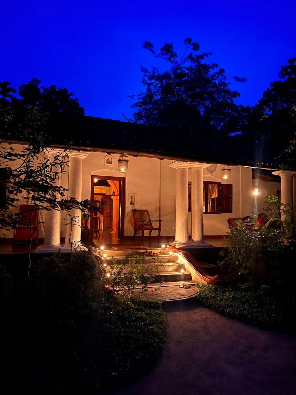 The veranda at dusk, lamps lit along its steps under a deep blue sky