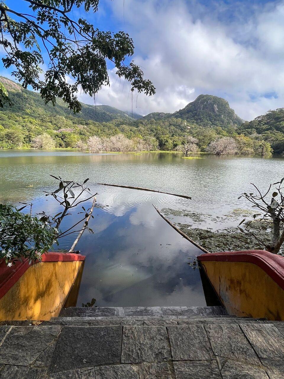 The lake from the stone landing between two yellow canoes, clouds and a wooded peak reflected in the water