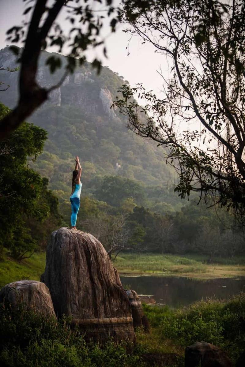 A sun salutation on a boulder above the lake at dawn, Ulpotha, Sri Lanka.